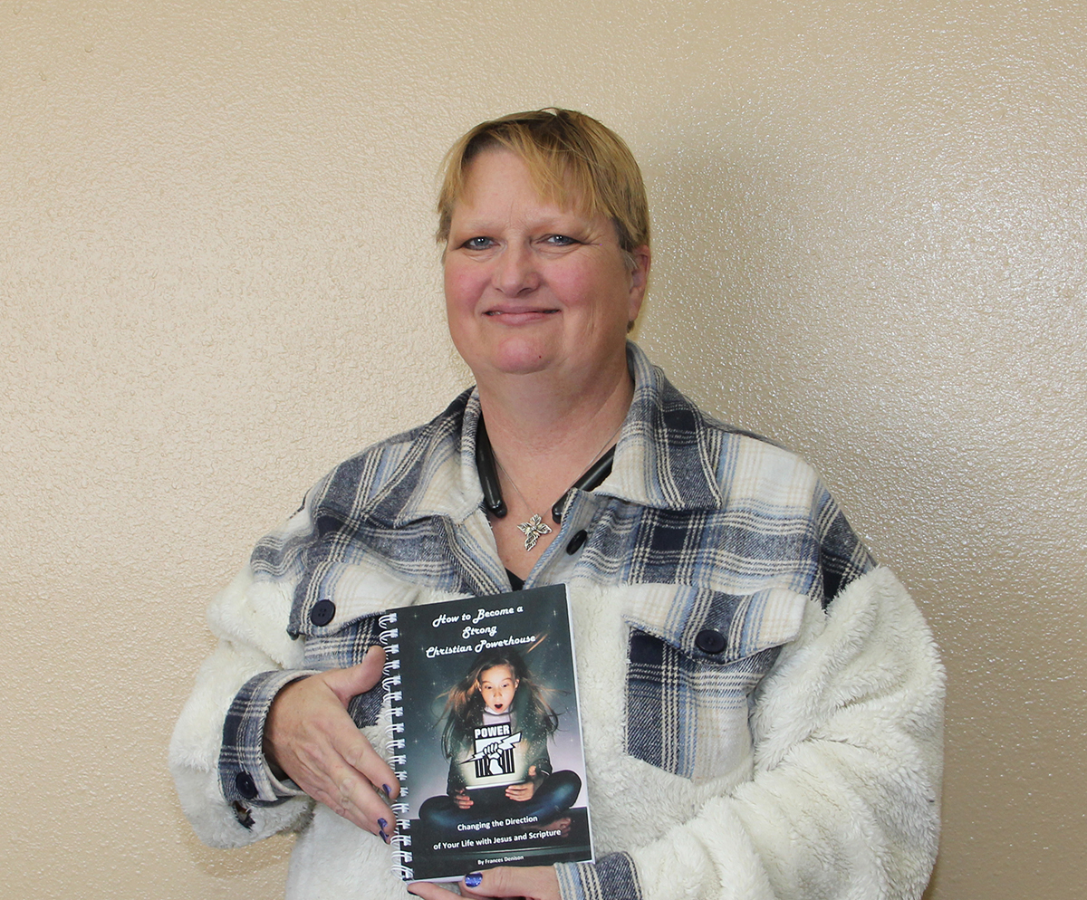 Photo By Chris Docter. Frances Denison shows off her recently published book, How to Become a Strong Christian Powerhouse: Changing the Direction of Your Life with Jesus and Scripture.