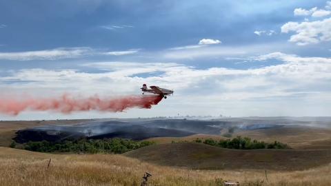 A single engine air tanker (SEAT) drops flame retardant on a grass fire at Allen, on Wednesday, August 27.